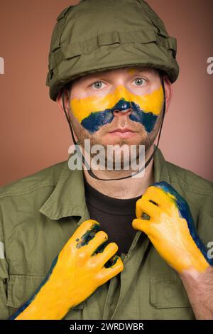 Uomo che esprime rispetto per l’Ucraina con colori nazionali sul viso Foto Stock