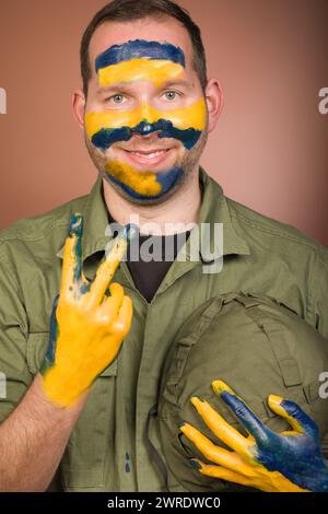 Uomo che esprime rispetto per l’Ucraina con colori nazionali sul viso Foto Stock