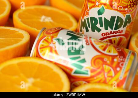 KIEV, UCRAINA - 7 LUGLIO 2023 bevanda all'arancia Mirinda con molte arance fresche su sfondo colorato Foto Stock