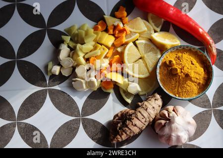 Ingredienti tritati con sidro di fuoco su sfondo grigio piastrellato. Foto dall'alto di curcuma, zenzero, pepe, aglio, cipolla e limone. Foto Stock