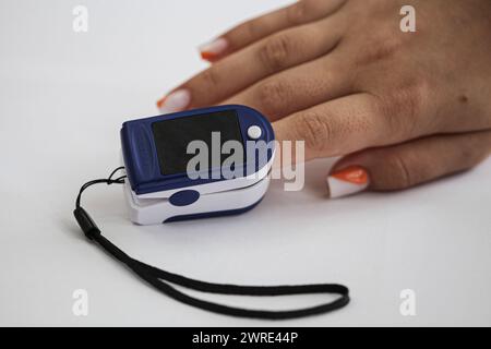 La mano di un giovane uomo con un pulsossimetro al dito. Monitoraggio del livello di ossigeno. Una ridotta ossigenazione indica lo sviluppo di Foto Stock