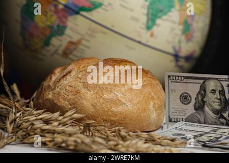 Crisi alimentare mondiale del grano, rappresentata da un globo, orecchie di grano e denaro, dollari, isolati su sfondo nero. Foto Stock