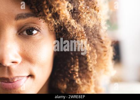 Primo piano di una donna birazziale con capelli ricci e occhi marroni caldi Foto Stock