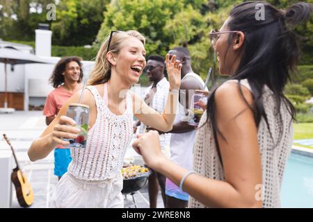 Gruppi diversi di amici che si godono una festa a bordo piscina, è evidente la risata Foto Stock