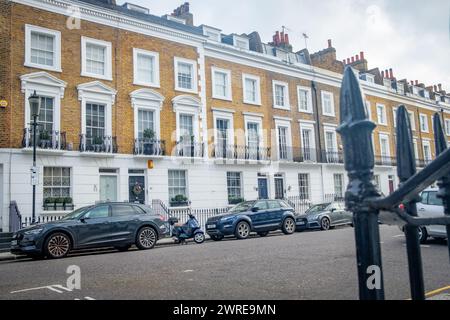 LONDRA - 11 GENNAIO 2024: Strada di eleganti case a schiera di stucchi bianchi nell'area SW3 di Kensington e Chelse Foto Stock