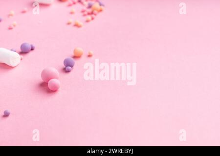 Piccoli caramelle e marshmallow di diversi colori e dimensioni si trovano su uno sfondo rosa. Molto spazio vuoto Foto Stock