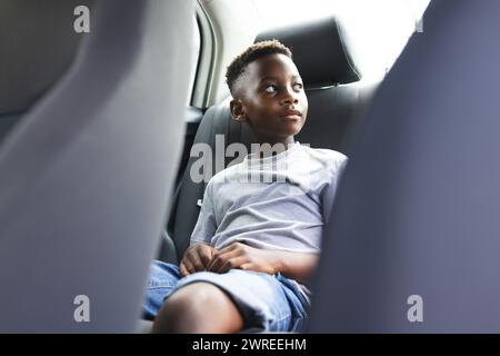 Ragazzo afroamericano seduto in macchina, guardando con attenzione fuori dal finestrino Foto Stock