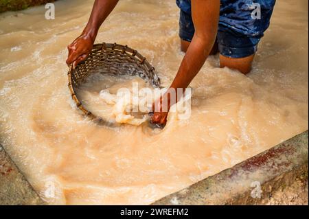 L'uomo lava la teglia di rattan con pietre preziose estratte, occupazione tradizionale in Sri lanka. Miniere di Meetiyagoda. Foto Stock