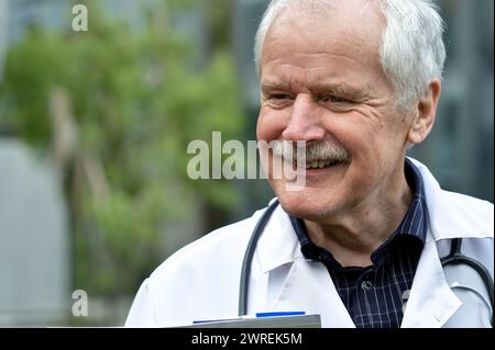 Medico anziano sorridente al paziente mentre dà la diagnosi. Foto Stock