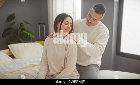 Una coppia amorevole gode di un momento sereno insieme nel comfort della loro moderna camera da letto, ritraendo l'intimità e la cura della famiglia. Foto Stock