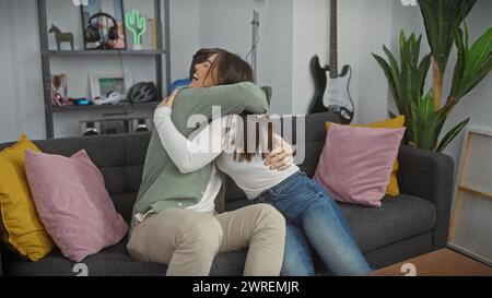 Una coppia amorevole abbraccia gioiosamente su un divano in un accogliente soggiorno, raffigurando un bellissimo e intimo momento tra un uomo e una donna. Foto Stock