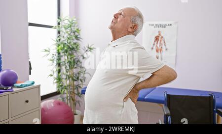 L'uomo anziano che soffre di dolori alla schiena esacerbati viene sottoposto a fisioterapia presso una clinica di riabilitazione Foto Stock