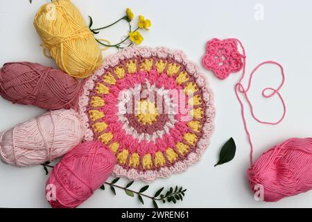 Concetto di hobby all'uncinetto. Ornamento decorativo realizzato a mano in filato di cotone biologico. Sfondo bianco con spazio per il testo. Foto Stock