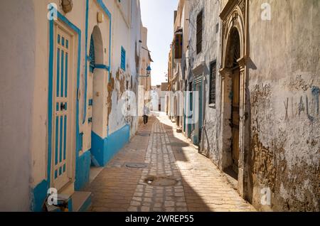 Un giovane cammina lungo uno stretto vicolo all'interno dell'antica medina di Kairouan, in Tunisia. La città è un sito patrimonio dell'umanità dell'UNESCO e la quarta più Santa Foto Stock