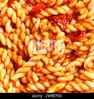 Primo piano di deliziosi fusilli italiani in salsa di pomodoro con erbe visibili, ideale per temi culinari. Foto Stock