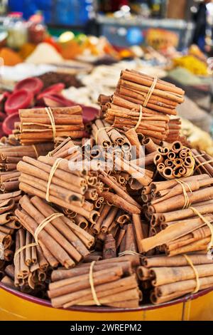 Fasci di bastoncini di cannella accatastati in un ambiente di mercato, che offrono un aroma ricco e un sapore caldo. Foto Stock