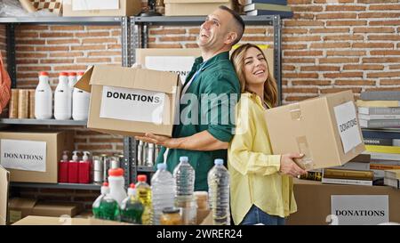 Uomini e donne volontari che tengono pacchetti di donazioni sorridenti al centro di beneficenza Foto Stock