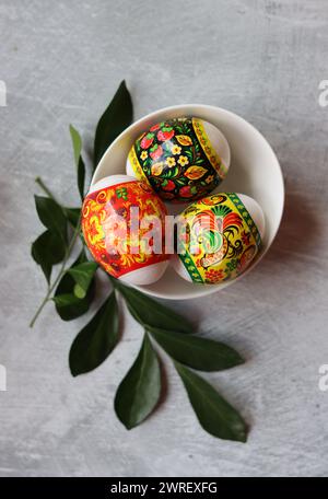 Uova di Pasqua su un tavolo. Natura morta con fiori bianchi e uova. Vista dall'alto delle uova colorate su un tavolo. Offerta per le vacanze di Pasqua. Foto Stock