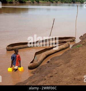 OMO VALLEY, ETIOPIA - 23 NOVEMBRE 2011: L'uomo raccoglie l'acqua in contenitori dal fiume Omo vicino a Turmi il 23 novembre 2011 nella valle di Omo, Etiopi Foto Stock