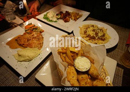 Primo piano: Pesce e patatine fritte con pasta al formaggio e bistecca di maiale Foto Stock