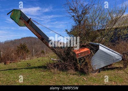 Attrezzature agricole abbandonate in un campo ricoperto di alberi e piante nella Virginia rurale, Stati Uniti Foto Stock