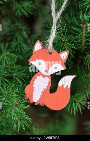 Giocattolo di volpe in legno appeso al ramo dell'albero di Natale. Decorazioni natalizie ecologiche. Foto Stock