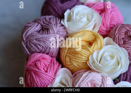 Bouquet di palline di filato di cotone in una scatola di legno. Foto colorata di filati organici rosa tenue. Concetto di hobby e svago. Foto Stock