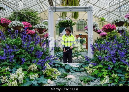 Un giardiniere che innaffia piante nel giardino d'inverno, Fitzroy Gardens, Melbourne, Victoria, Australia Foto Stock