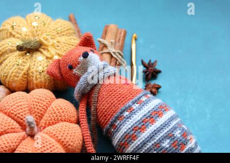 Volpe giocattolo lavorata a maglia, palle di filato e decorazioni autunnali su sfondo testurizzato con spazio per il testo. Bel giocattolo amigurumi. Foto Stock