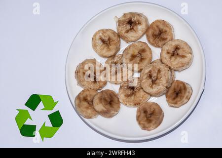 Un piatto con fette di banane e patatine di colore nero, cioè, sono quasi viziate, stanno su uno sfondo bianco, come segno del suo Foto Stock
