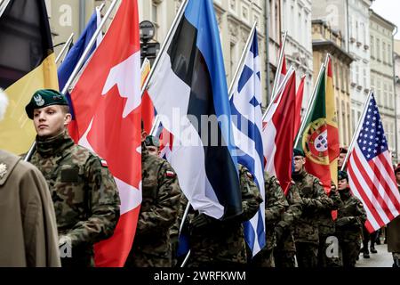 I soldati polacchi marciano le bandiere dei membri della NATO mentre la Polonia celebra il 25. Anniversario dell'adesione all'alleanza del Nord Atlantico nella piazza principale nella città vecchia di Cracovia, in Polonia, il 12 marzo. 2024. Foto Stock