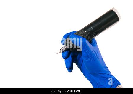 La mano dell'artista del tatuaggio orizzontale in un guanto blu afferra una macchina per tatuaggi, isolata sul bianco, a simboleggiare la disponibilità a creare arte. Copia spazio. Conc Foto Stock