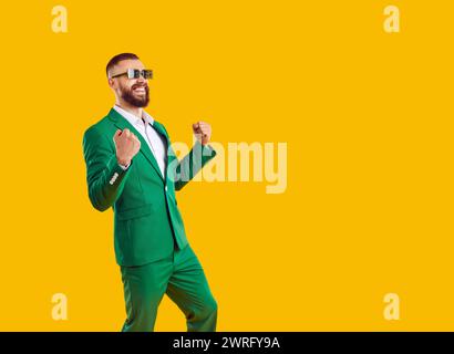 Felicissimo showman uomo d'affari con costume verde e occhiali da sole che mostrano un gesto e un sorriso. Foto Stock