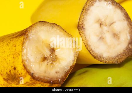la foto di due metà di banana che sono macro posato su uno sfondo giallo. Una metà della banana è matura e una sta per rovinare. Pol. Di alta qualità Foto Stock