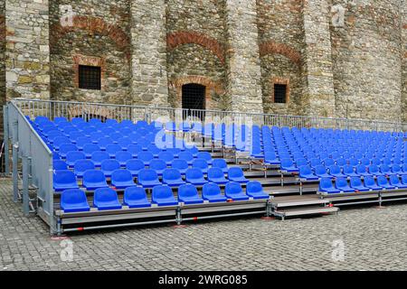 Sala concerti all'aperto con file vuote di posti blu, struttura mobile in metallo con sedili in plastica Foto Stock