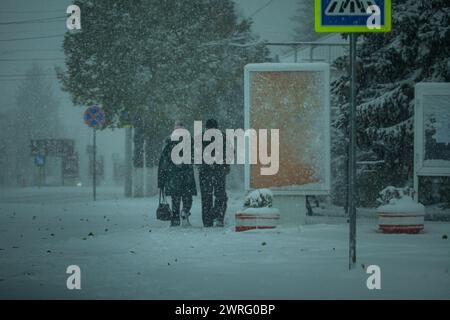 Una strada innevata con persone in tempesta, bufera o nevicate In inverno in cattive condizioni atmosferiche nella città. Tempo invernale estremo Condizioni nel Nord.PE Foto Stock