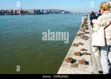 Budapest, Ungheria - 3 marzo 2024: Visitatori al memoriale delle scarpe di ferro per le vittime dell'Olocausto ebraico 2WW Foto Stock