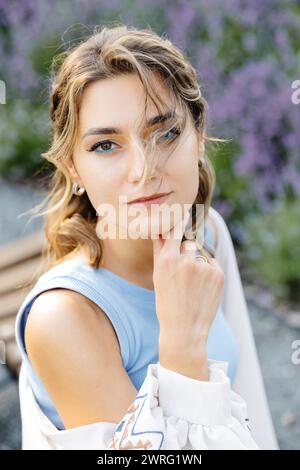 Una donna con gli occhi azzurri si trova in una posa sicura, pronta per una fotografia. Foto Stock