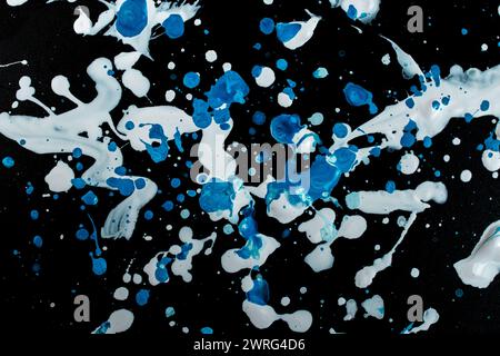 Spruzzi di vernice bianca e blu sparsi su sfondo nero Foto Stock