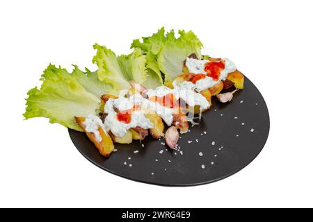 Patate cotte al forno con salsa tzatziki e pasta di peperoncino rosso su un piatto di ceramica nera con foglie di lattuga, isolate su sfondo bianco Foto Stock