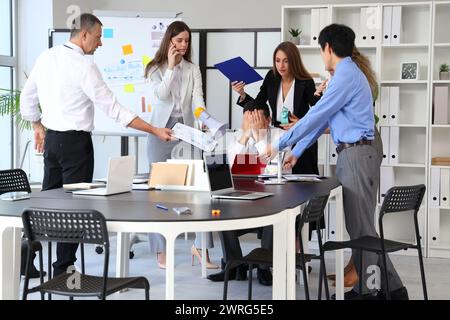 Uomo d'affari maturo che soffre di colleghi rumorosi in ufficio Foto Stock