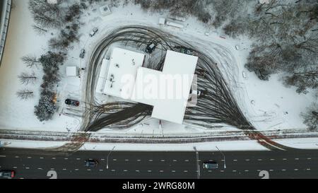 Fotografia con droni di una stazione di servizio e impronte di pneumatici direttamente sopra la stazione di servizio durante il giorno nuvoloso invernale Foto Stock