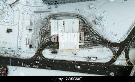 Fotografia con droni di una stazione di servizio e impronte di pneumatici direttamente sopra la stazione di servizio durante il giorno nuvoloso invernale Foto Stock