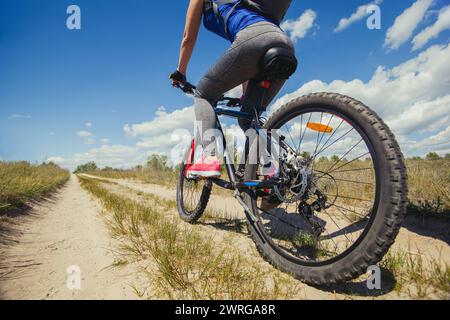 Una giovane donna - un'atleta cavalca in mountain bike fuori città in una pineta, in una giornata estiva. Foto Stock