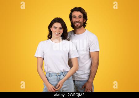 Una coppia giovane e felice che indossa t-shirt casual bianche e jeans blu in piedi vicini Foto Stock