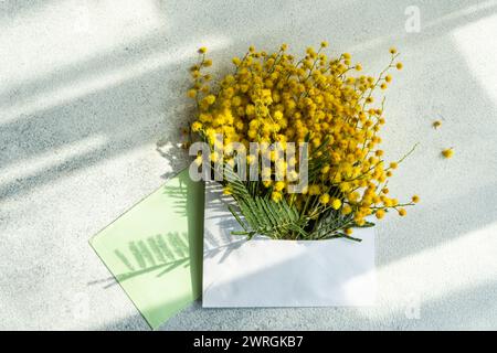 Vista dall'alto di un mazzo di fiori di mimosa gialli in una busta su un tavolo Foto Stock