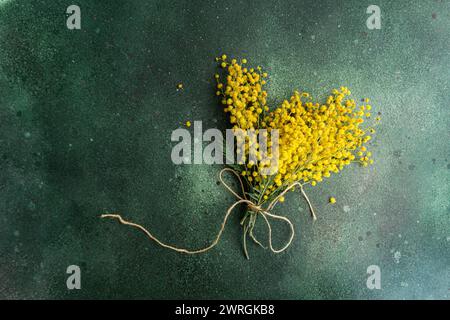 Vista dall'alto di un mucchio di steli di mimosa gialli appena raccolti legati con un filo su un tavolo Foto Stock