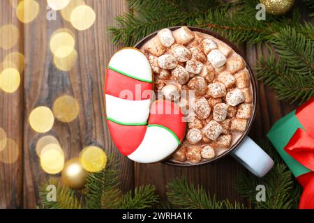 Gustosi biscotti natalizi a forma di canna da zucchero, decorazioni e cacao con marshmallow su un tavolo di legno, piatto. Spazio per il testo Foto Stock