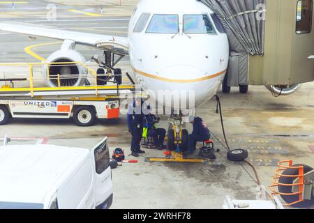 30 ottobre 2023 EWR Newark NJ US United Airlines meccanici di manutenzione degli aeromobili al lavoro seduti sui suoi stalli sotto l'aereo Foto Stock