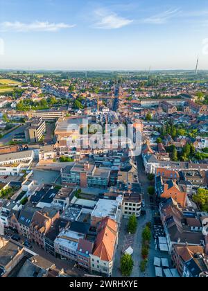 Si tratta di un'immagine aerea che cattura il cuore di Halle, in Belgio, nel dolce abbraccio dell'ora d'oro. Il fascino storico della città si intreccia con gli aggiornamenti moderni, mentre i tetti in terracotta si mescolano con le strutture contemporanee. Le strade formano un motivo labirintico, che porta gli occhi attraverso il denso nucleo urbano verso gli spazi aperti più verdi che circondano la città. Le ombre emesse dal sole basso accentuano l'aspetto tridimensionale degli edifici, aggiungendo profondità e contrasto alla scena. In lontananza, si può notare il delicato passaggio dalla città alla pastorale, evidenziando Halles con Foto Stock